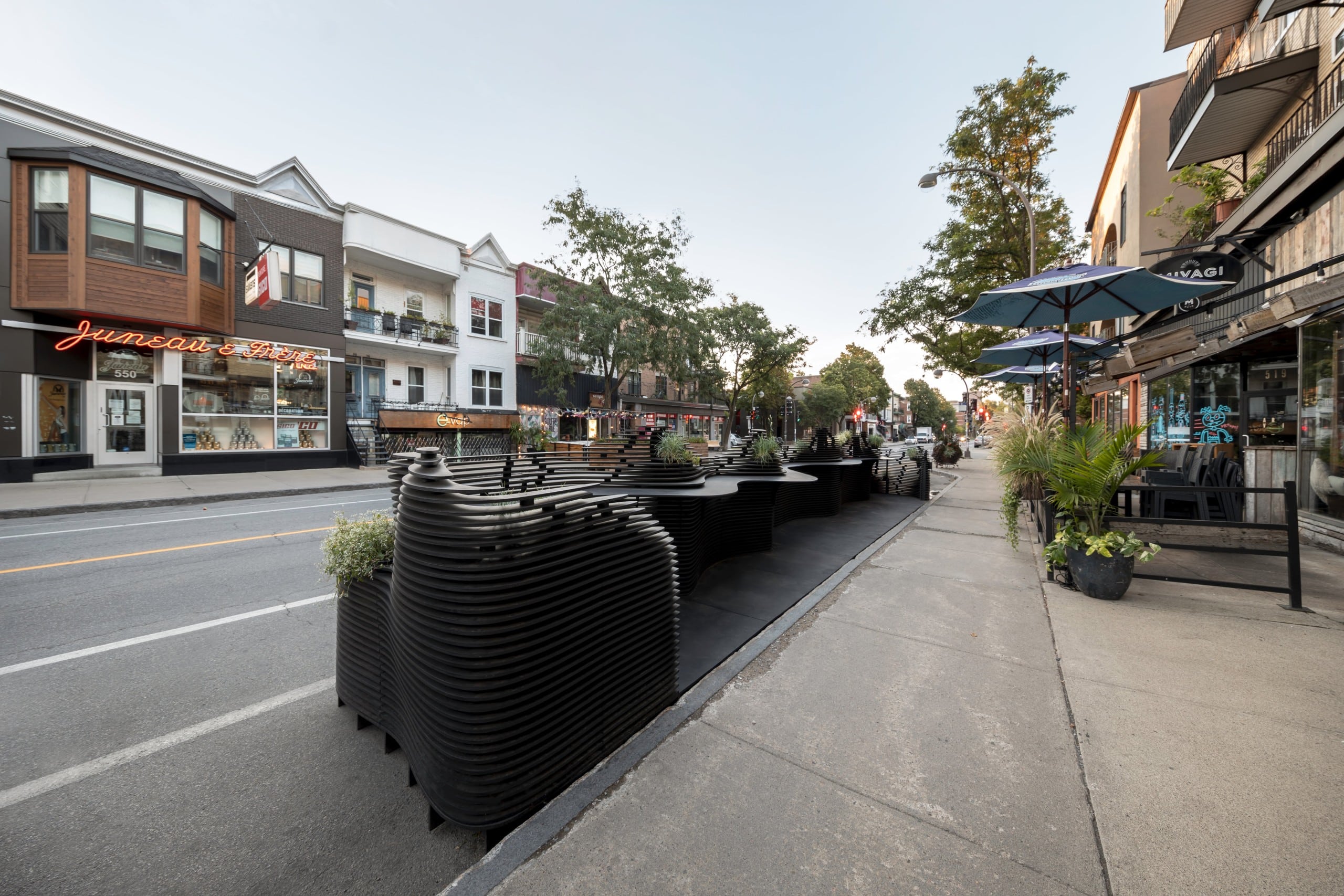 Blick auf die innere Seite eines Parklets aus schwarzem Holz, das auf einer Straße steht. Quinzhee Architecture und atelier mock/up, Parklet Miyagi, Québec, Foto: 1Px