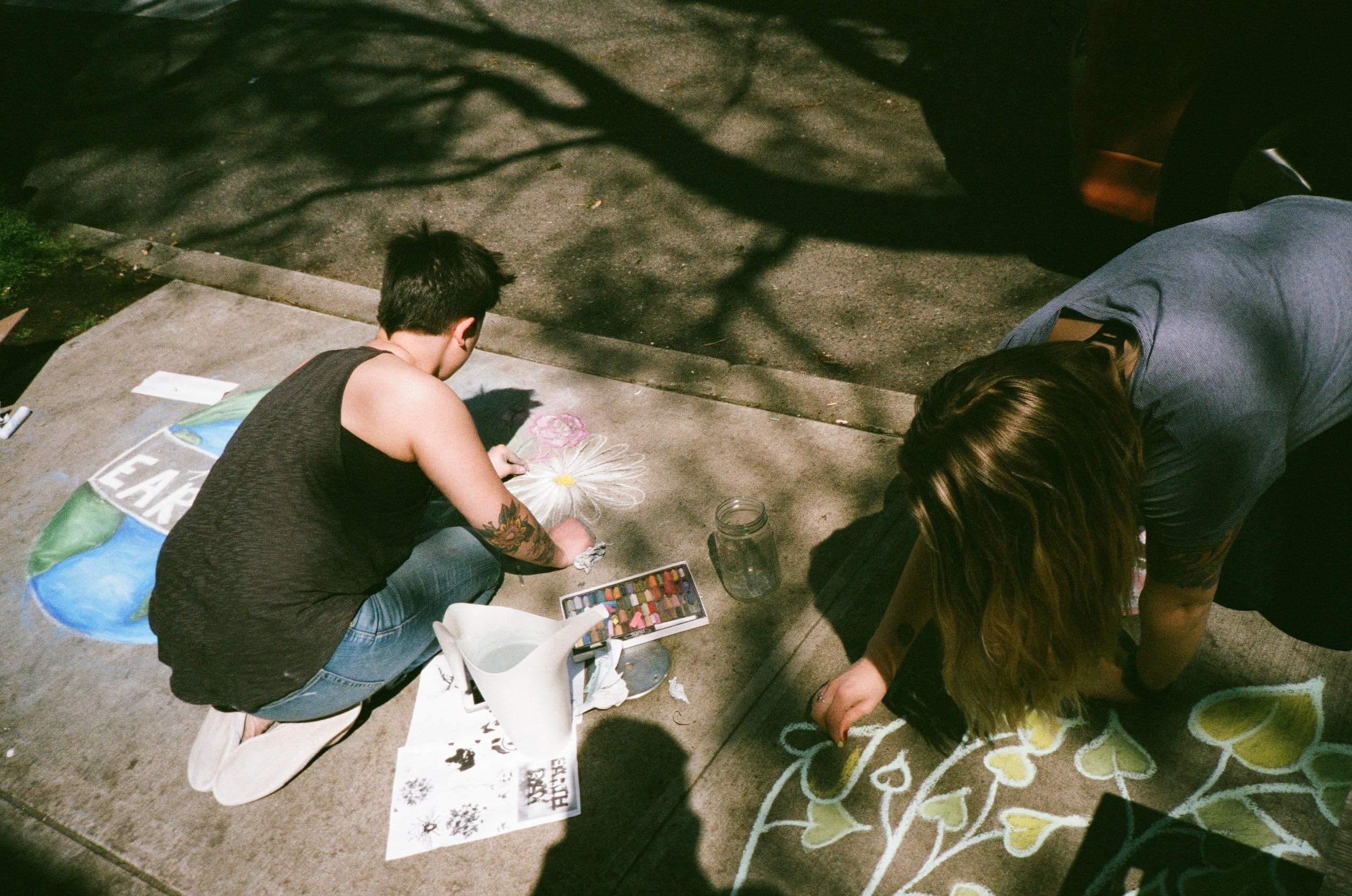 Zwei Personen zeichnen mit bunter Kreide auf der Straße © Photo by Dino Demopoulos on Unsplash