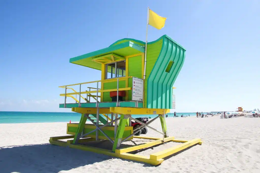 Ein Strandwächterhäuschen aus Holz in leuchtenden Grüntönen und Gelb steht auf einem Strand. Der Architekt William Lane entwarf sechs verschiedene Prototypen für die Lifeguard Towers am Strand von Miami Beach. Foto: William Lane Architect
