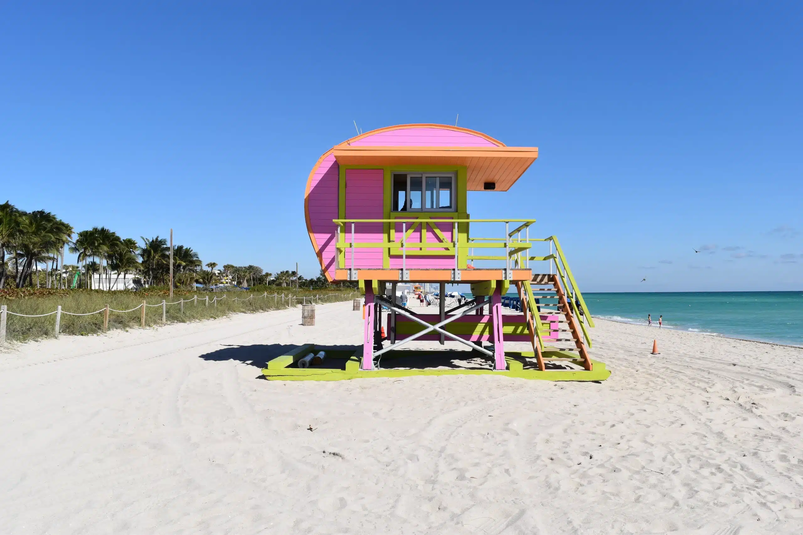 Ein hölzernes Wasserwachthäuschen mit geschwungenem Dach in Orange, Rosa und Gelb. Miami Beach, Lifeguard Tower, William Lane, Foto: Archiv Architekten
