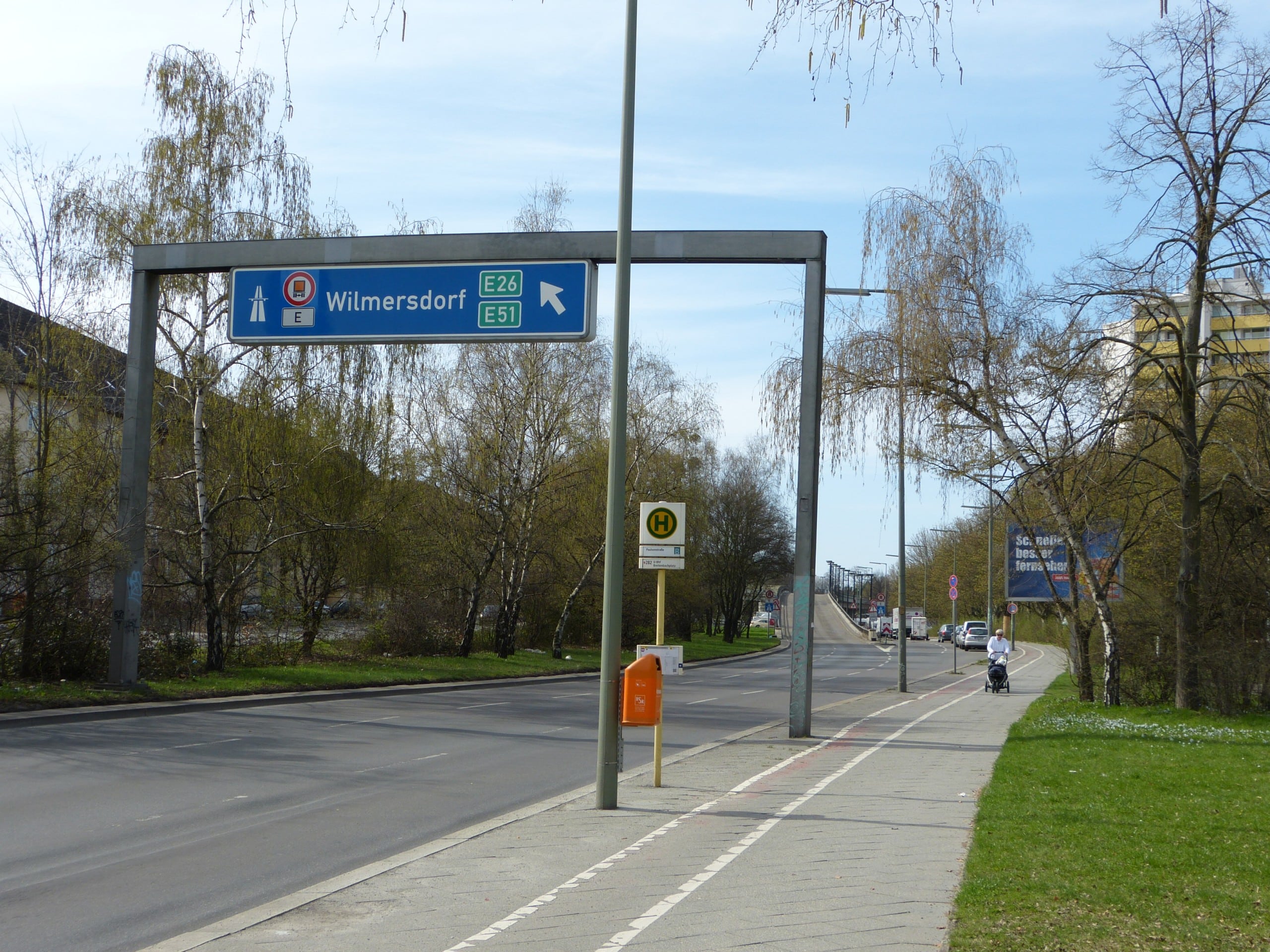 Eine zweispurige Straße führt in der Ferne auf eine Brücke. Darüber steht ein Verkehrsschild mit dem Symbol für eine Autobahnauffahrt. Steglitz-Schildhornstraße – Bearbeitungsgebiet des diesjährigen AIV Schinkel Wettbewerb 2023. Credits: Muns, CC BY-SA 3.0, via Wikimedia Commons