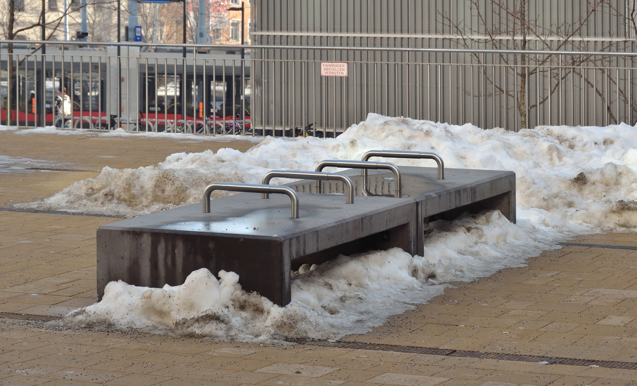 Eine Betonbank mit mehreren Armlehnen aus Metall, die die Sitzflächer unterteilen. Armlehnen an Bänken, wie hier vor dem Westbahnhof in Wien, können beim Aufstehen unterstützen – oder verhindern, dass man sich auf Bänke legt. Foto: Herzi Pinki, CC BY-SA 4.0, via Wikimedia Commons