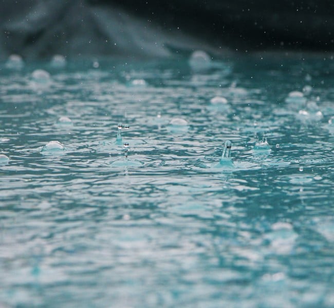 Regentropfen fallen in eine Pfütze. Wie kann ein nachhaltiger Umgang mit Regenwasser aussehen? Der Mall Umweltpreis sucht nach Antworten. Credit: Inge Maria via Unsplash