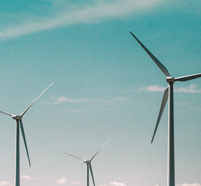 Vor einem blauen Himmel sehen drei Windräder. Die Bundesregierung hat das Ziel, bis 2030 Strom aus erneuerbaren Energien zu verdoppeln. Das „Wind-an-Land-Gesetz“ soll dabei helfen.