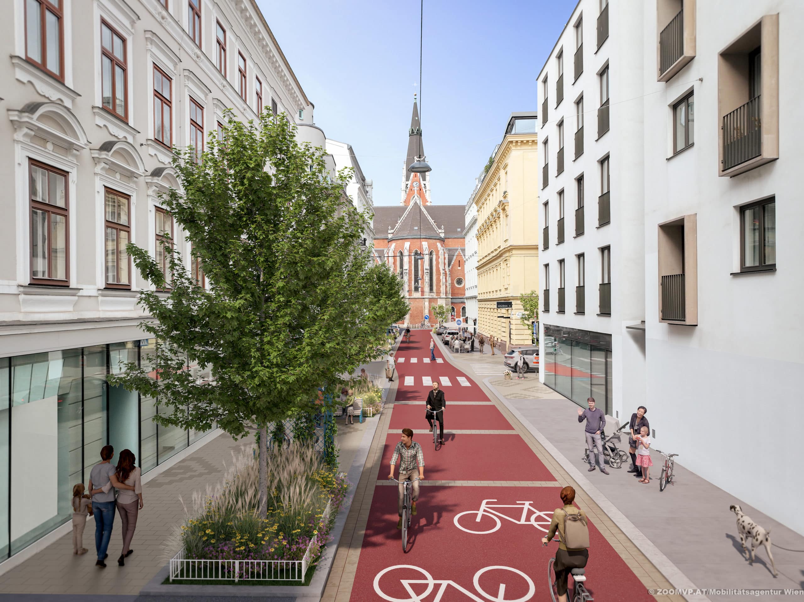 Im Hintergrund die Karlskirche. Darauf fluchtet eine rot asphaltierte Fahrradstraße zu. Sie wird von Bäumen begleitet.