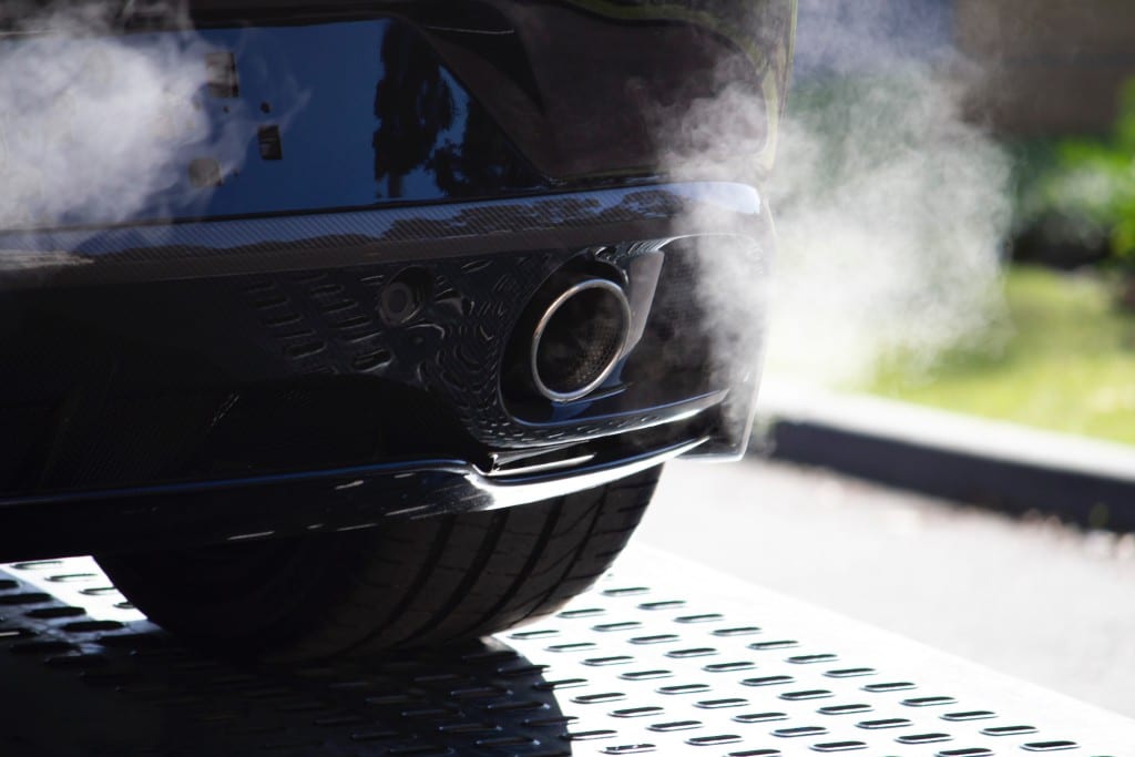 Das Bild zeigt einen Auto Auspuff aus dem Dampf steigt.