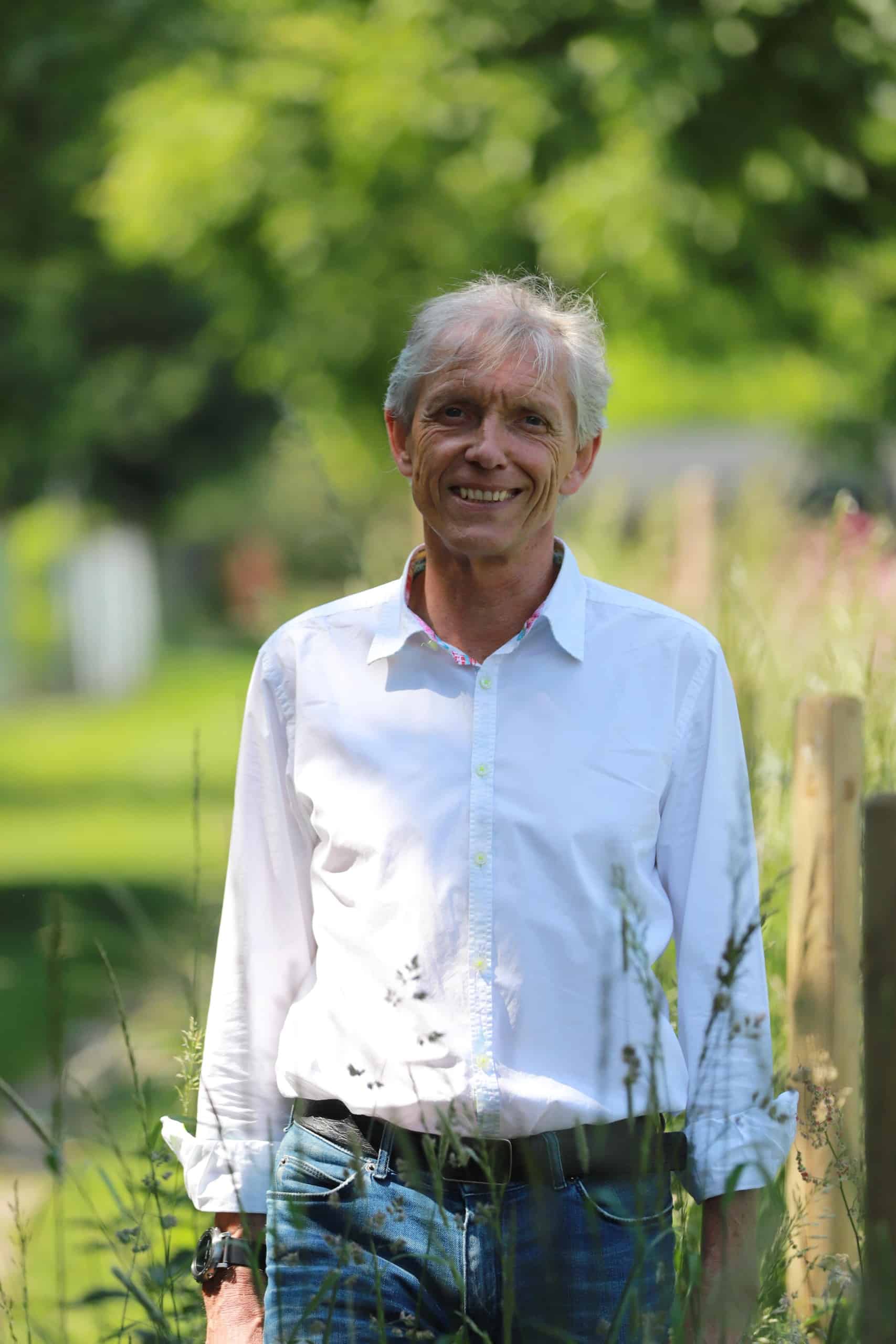 Bildbeschreibung: Ein lächelnder Mann in weißem Hemd vor grünem Hintergrund. Dirk Schelhorn war gelernter Bildhauer, machte sich als Landschaftsarchitekt selbstständig und führte bis 2020 sein Planungsbüro LS2. Foto: Sandra Escher
