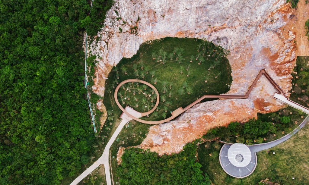 Vogelperspektive auf einen Park, in einem Felskrater aus hellgrauen und orangenen Felsen verläuft ein gewundener Pfad auf stegen. Der Tangshan Quarry Park in Nanjing von Z+T Studio erhält den Rosa Barba Prize 2023. Foto: Hai Zhang